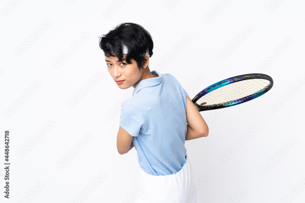 Young Vietnamese tennis player woman over isolated white wall playing tennis Young Vietnamese tennis player woman over isolated white wall playing tennis