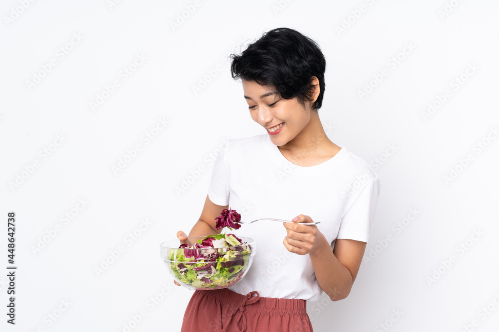 Young Vietnamese woman with short hair holding a salad over isolated background Young Vietnamese woman with short hair holding a salad over isolated background