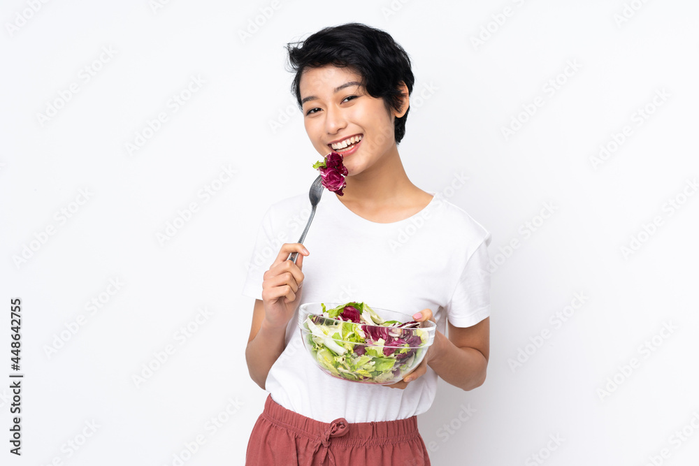 Young Vietnamese woman with short hair holding a salad over isolated background Young Vietnamese woman with short hair holding a salad over isolated background