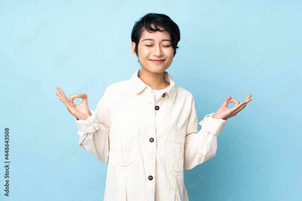 Young Vietnamese woman with short hair over isolated background in zen pose Young Vietnamese woman with short hair over isolated background in zen pose