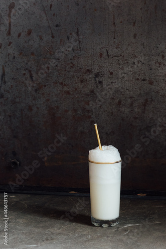 Ramos gin fizz milkshake white foam in gold-rimmed tall glass with gold drinking straw photo