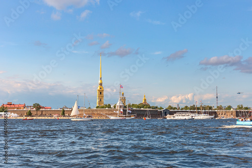 small sailboats and a white tourist ship are moored on the Neva at the walls of the Peter and Paul Fortress