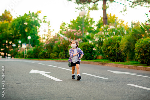 a beautiful little girl, a schoolgirl, is standing on the road, with a backpack, holding a diary in her hands