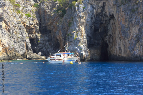 Battello con turisti in tour presso le grotte della costiera del Cilento © ematon
