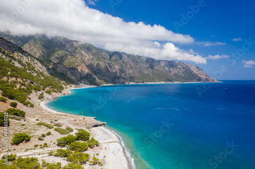 Aerial view of clouds over large mountains on a coastline surrounded by clear, blue ocean (Agia Roumeli, Crete) © whitcomberd