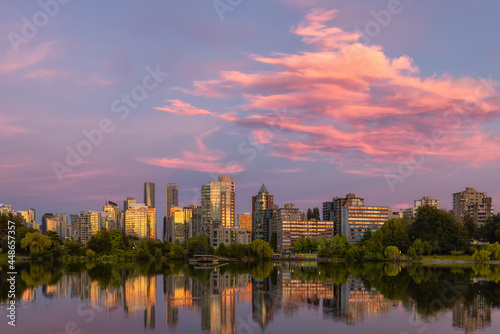 View of Lost Lagoon in famous Stanley Park in a modern city with buildings skyline in background. Colorful Sunset Sky. Downtown Vancouver  British Columbia  Canada.