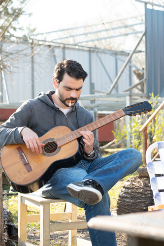 hombre 35-40 tocando guitarra criolla en tarde soleada de invierno