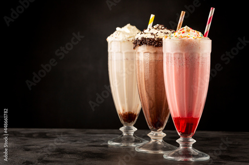 Three glasses of milkshake with assorted flavors. Chocolate, vanilla and strawberry milkshake.