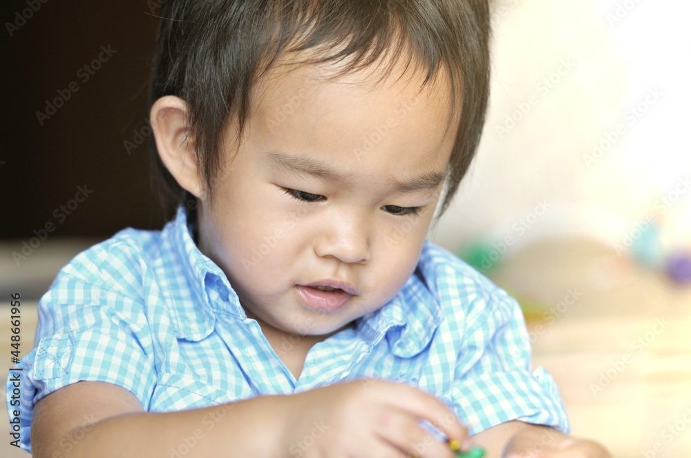 Little Chinese boy playing toy in bedroom. Young kid with colorful educational toys on floor. Kids at home or daycare conceptual Little Chinese boy playing toy in bedroom. Young kid with colorful educational toys on floor. Kids at home or daycare conceptual