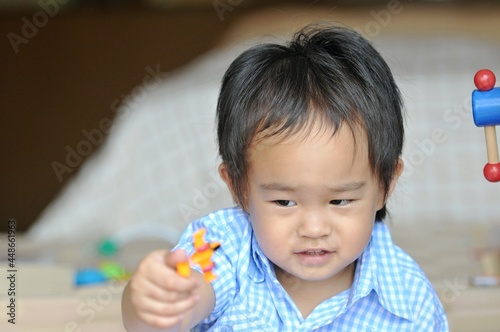 Little Chinese boy playing toy in bedroom. Young kid with colorful educational toys on floor. Kids at home or daycare conceptual 
