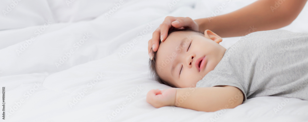 Young asian mother touch head of little baby girl with tender on bed in the bedroom, mom love newborn and care, woman with expression with child together, parent and daughter, family concept. Young asian mother touch head of little baby girl with tender on bed in the bedroom, mom love newborn and care, woman with expression with child together, parent and daughter, family concept.