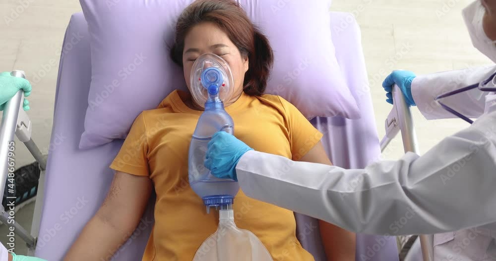 Team of medical person, doctor and nurse, moving femal patient on bed and using resuscitator face mask equipment holp for breating in emergency case. Take from top view or top down high angle.