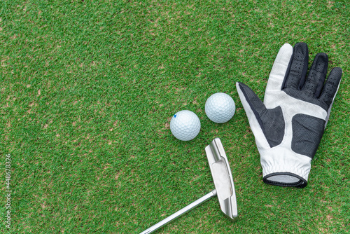 golf glove , white golf ball and tee put on green grass of golf course ,This golf objects for play