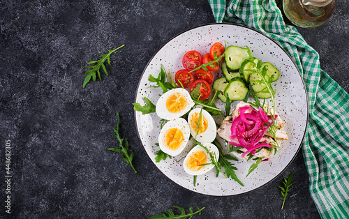 Breakfast. Boiled eggs salad with greens, cucumbers, tomato and sandwich with ricotta cheese, fried chicken fillet and red onion. Keto/paleo lunch. Top view, overhead