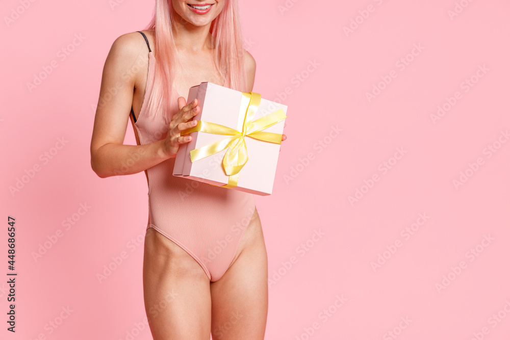 Cropped shot of woman in swimsuit holding cute gift box, standing isolated over pink background. Holiday, birthday concept Cropped shot of woman in swimsuit holding cute gift box, standing isolated over pink background. Holiday, birthday concept