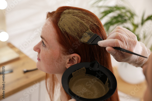 Photography Professional hairdresser dyeing woman's hair with henna in beauty salon