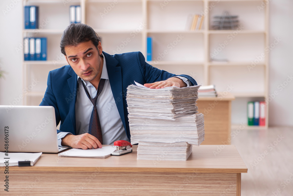 Young male employee unhappy with excessive work Young male employee unhappy with excessive work