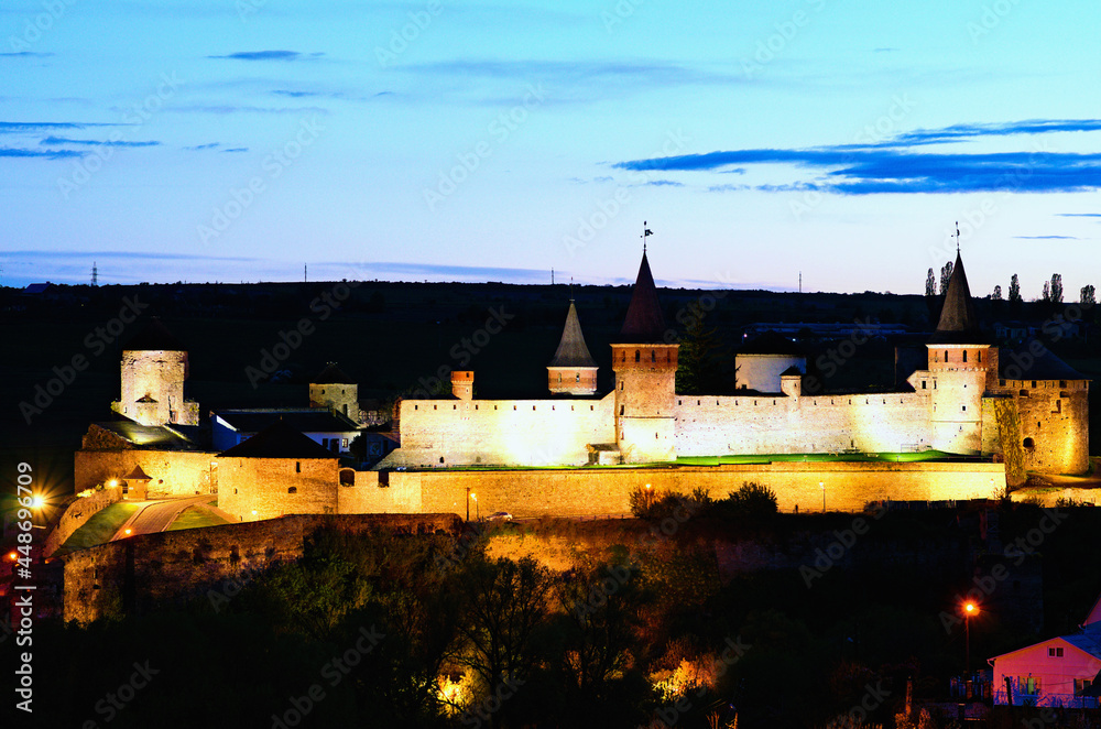 Naklejka premium Night light landscape of illuminated medieval castle. Colorful sky in the background. Famous touristic place and romantic travel destination