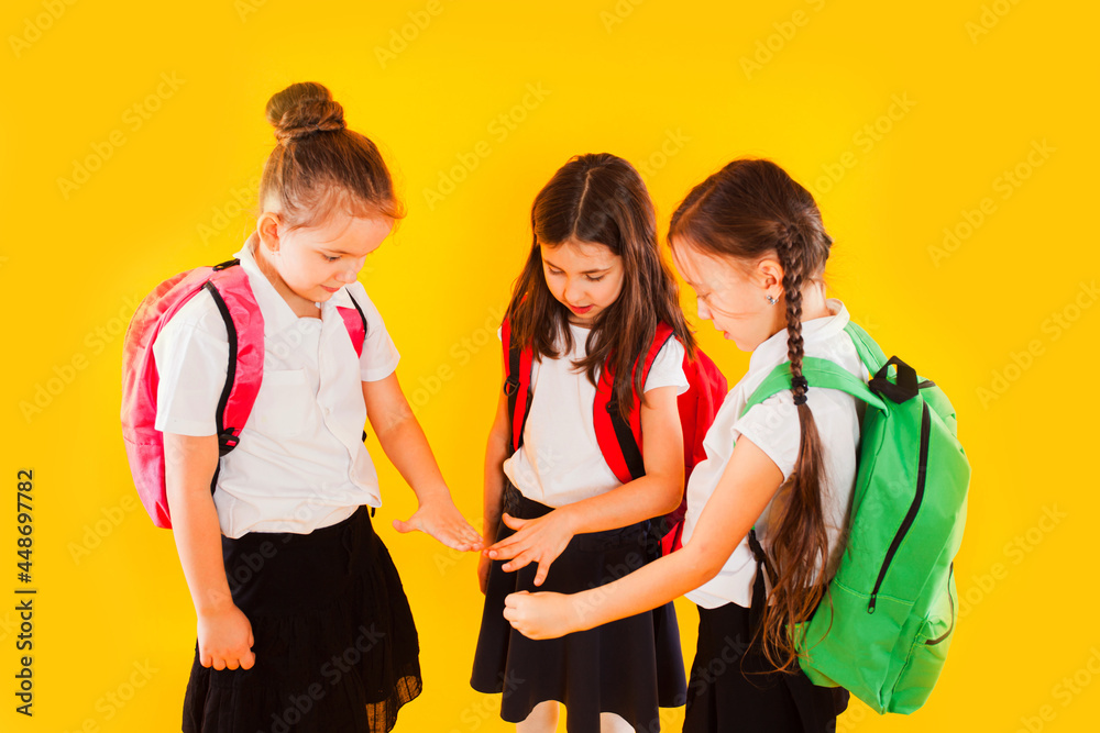 Cute girls in uniform with backpacks on yellow background Cute girls in uniform with backpacks on yellow background