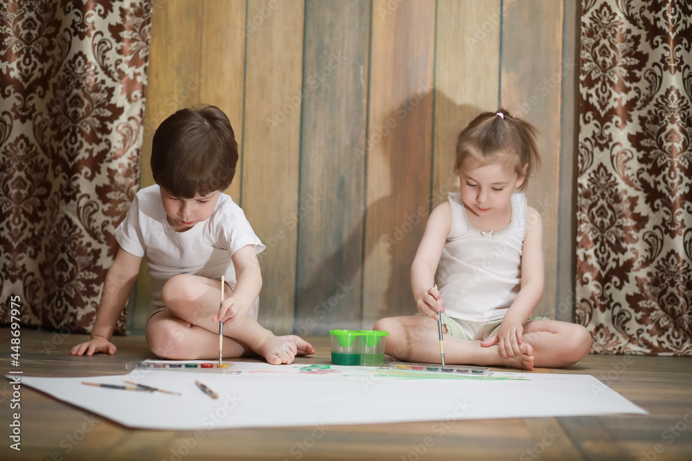Little children paint on a large sheet of paper Little children paint on a large sheet of paper