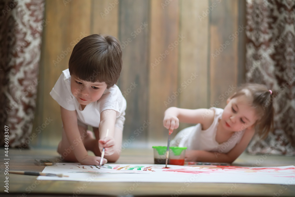 Little children paint on a large sheet of paper Little children paint on a large sheet of paper