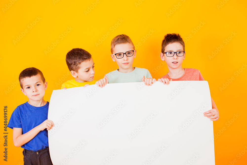 The different little boys are holding a big white paper The different little boys are holding a big white paper