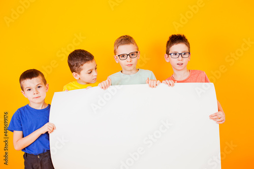 The different little boys are holding a big white paper