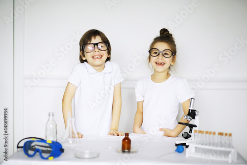 Two cute children at chemistry lesson making experiments on white background