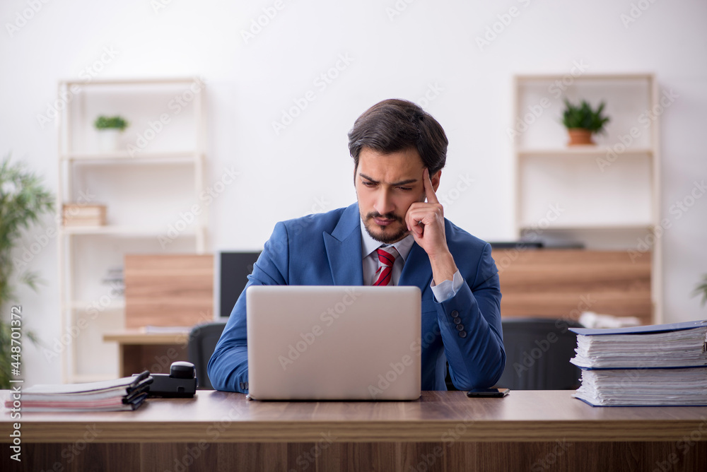 Young male employee sitting at workplace Young male employee sitting at workplace