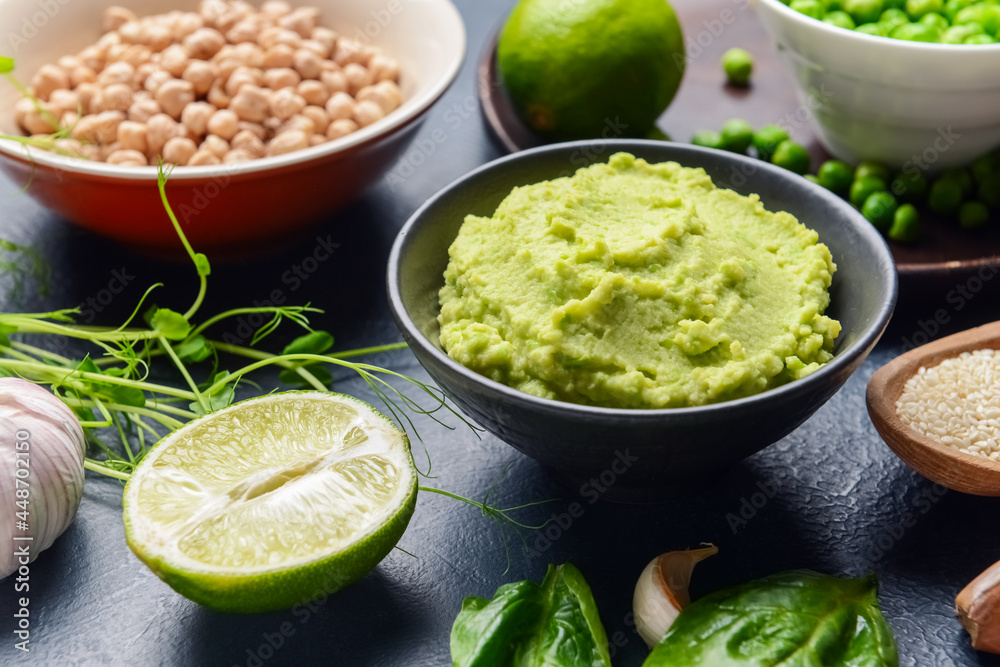 Bowl with tasty green pea hummus, lime and chickpeas on dark background, closeup Bowl with tasty green pea hummus, lime and chickpeas on dark background, closeup