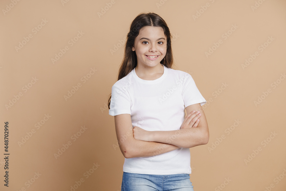 Pleasant, charming teenage girl crossed her arms over her chest smiling sweetly. Beautiful little girl on a brown background Pleasant, charming teenage girl crossed her arms over her chest smiling sweetly. Beautiful little girl on a brown background