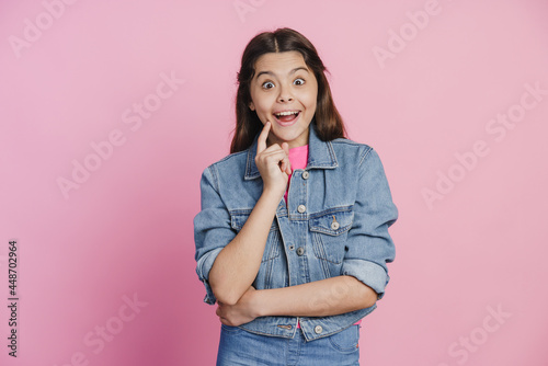 Cute, teenage girl in a denim jacket has a great idea. The girl touches her face with her index finger