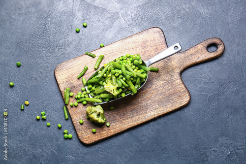 Scoop with frozen green vegetables on dark background