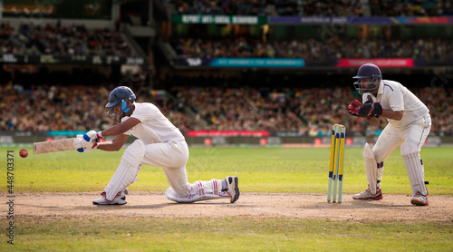 Cricketer batsman hitting a shot during a match on the pitch photo