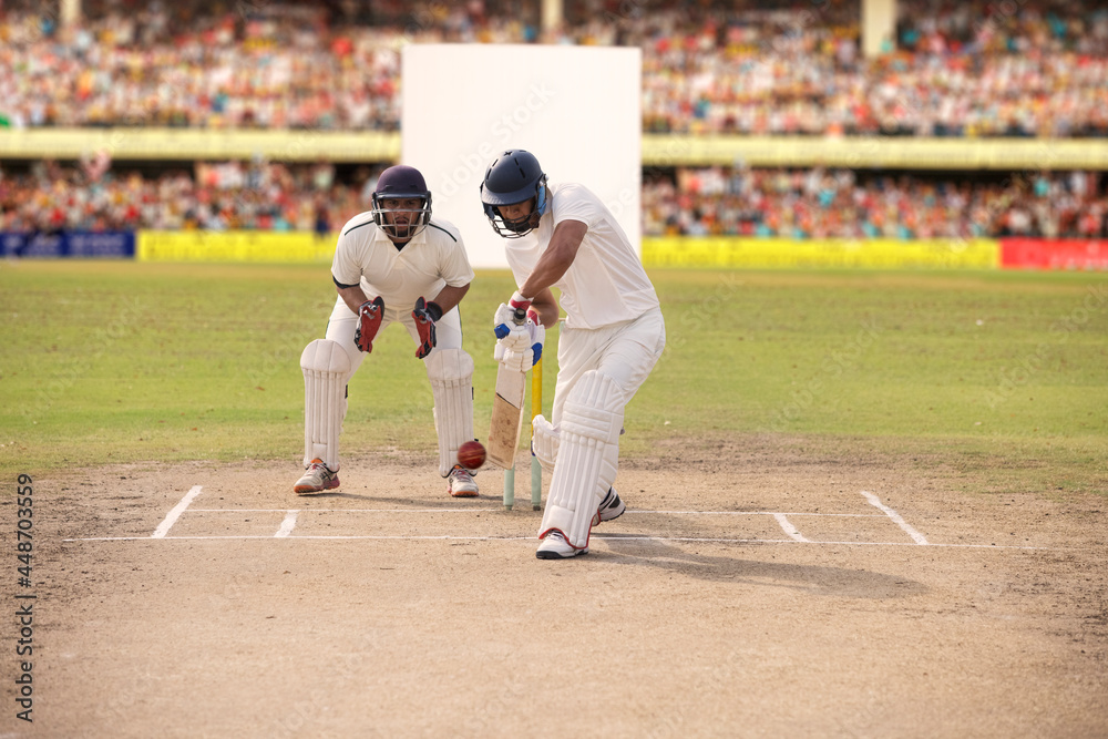 Cricketer batsman hitting a shot during a match on the pitch - obrazy, fototapety, plakaty 