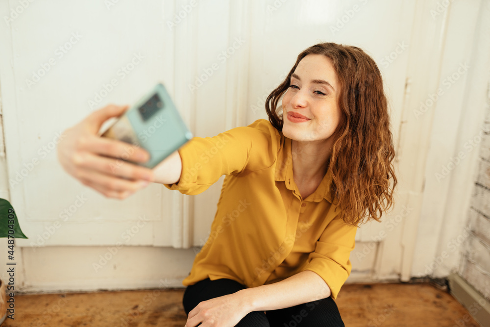 Cute young woman posing for a selfie on her mobile phone Cute young woman posing for a selfie on her mobile phone