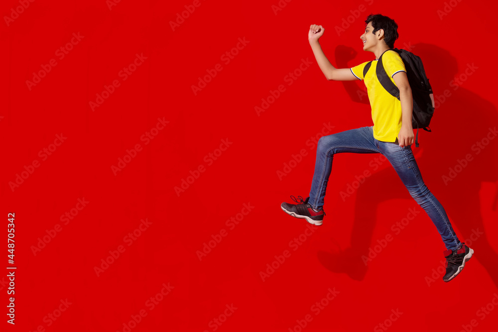 AN EXCITED TEENAGER JUMPING AND POSING WHILE WEARING SCHOOL BAG
