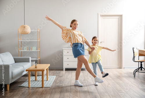 Young woman and her little daughter dancing at home