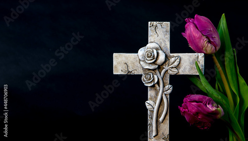 Isolated ornate religious cross with a tulip flower on a dark background. Moment of grief at the end of a life. Last farewell. Sympathy card with Copy space. photo