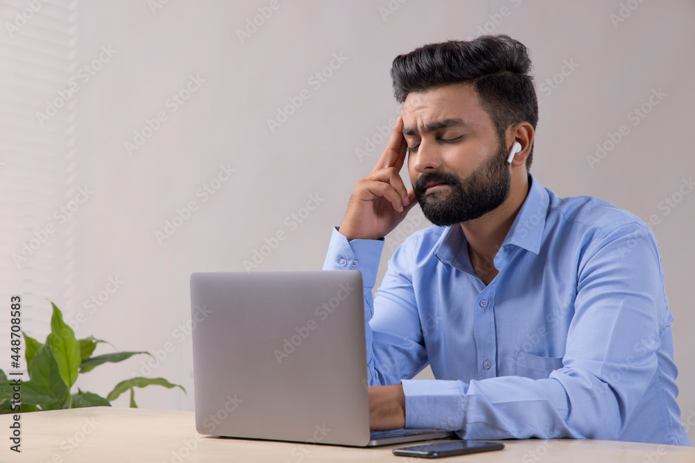 A YOUNG MAN SITTING AND THINKING WHILE WORKING A YOUNG MAN SITTING AND THINKING WHILE WORKING