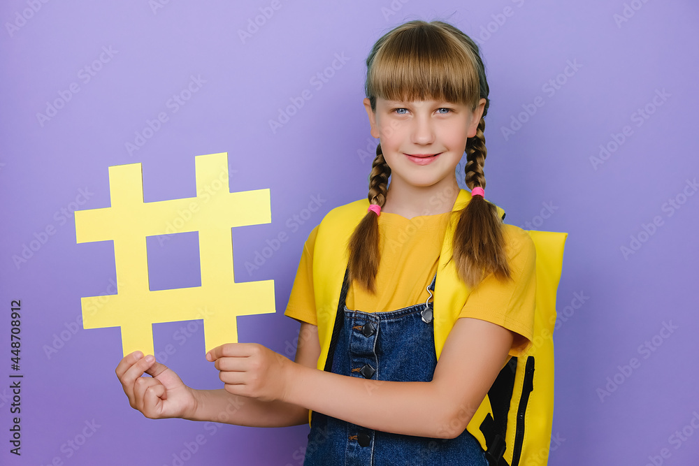 Portrait of cute smiling school girl kid with yellow backpack showing