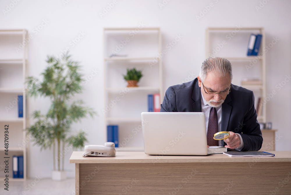 Old male employee sitting at workplace Old male employee sitting at workplace