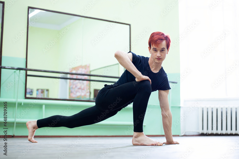 Male dancer in the dancing hall. Having stretching and warming up before intensive dance learning is essential to avoid injury