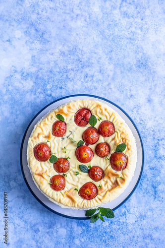 Savoury cheesecake with tomatoes decorated with mint, blue concrete background. Top view.