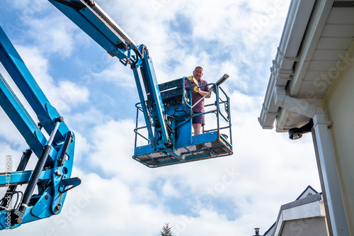 Foto Worker on a aerial access platform, cherry picker, cleaning house