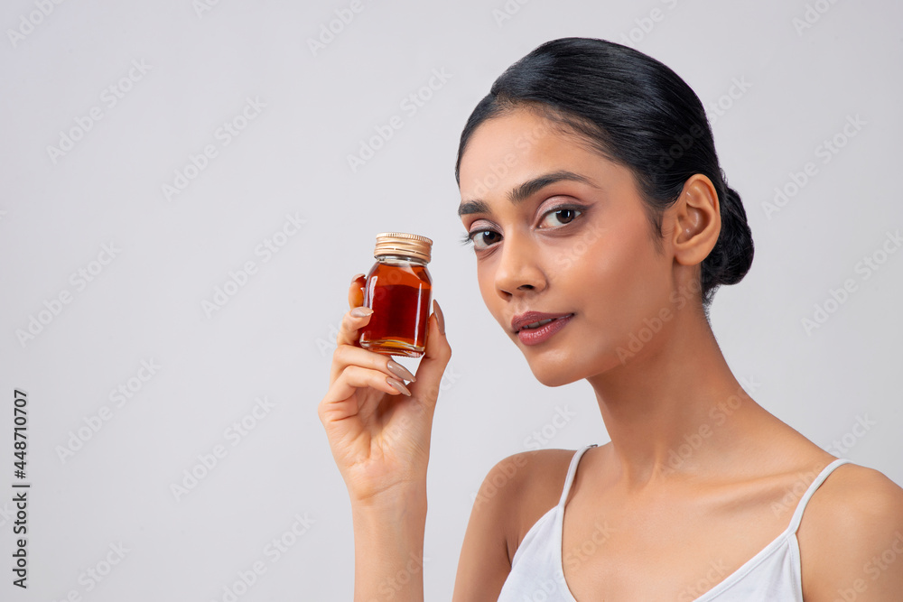 A young woman with clear,spotless skin holding a bottle of honey. A young woman with clear,spotless skin holding a bottle of honey.