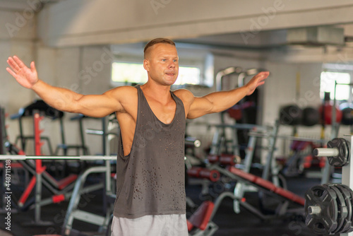 Fitness man warming up in gym. Male doing warm up stretching workout on gym background. © ARVD73