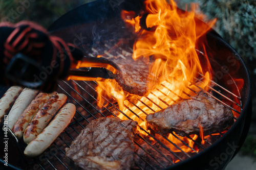 man turning steak on barbeque grill