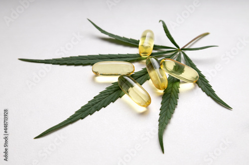 Several capsules drug on the fresh green cannabis leaf