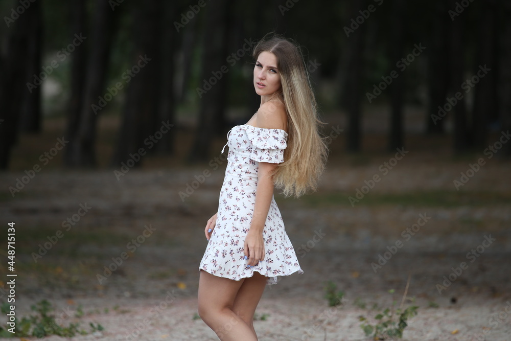 Young long haired woman in white dress near the forest Young long haired woman in white dress near the forest